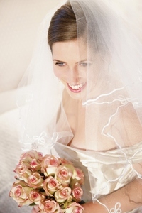 Smiling bride wearing a veil and holding a bouquet of roses