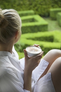 Woman Having Cappuccino Looking Out into Garden
