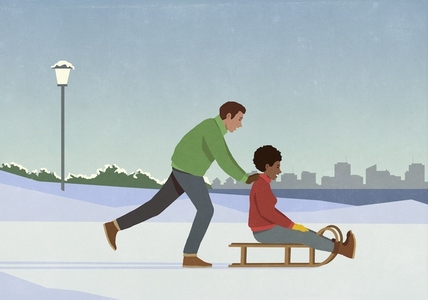 Boyfriend pushing girlfriend on sled in snowy winter city park