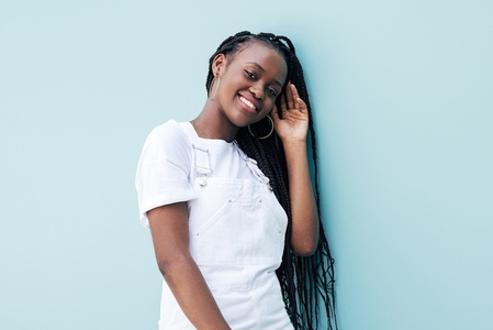 Smiling woman wearing white casual clothes standing at blue wall and looking at camera