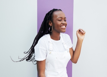 Young smiling female enjoying a good mood  Happy woman in white overalls standing at the wall