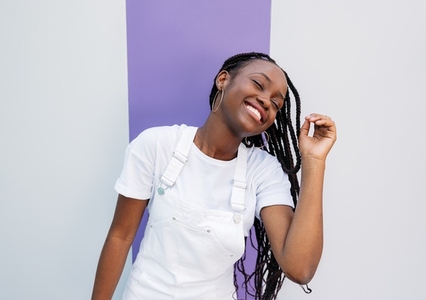 Young female with braids having fun  Girl in white overall with closed eyes