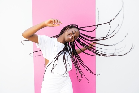 Young happy girl with braided hair having fun at white wall with pink stripe