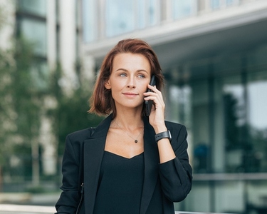 Middle aged businesswoman in formal clothes making phone call  Portrait of a young adult female with ginger hair talking on a mobile phone while standing outdoors