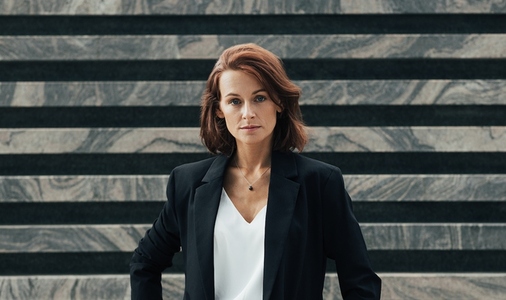 Portrait of a middle aged female in black formal wear looking at camera  Confident businesswoman posing while standing outdoors