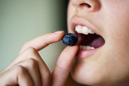 Crop teenage girl about to eat delicious organic blueberry