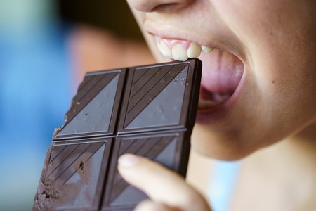 Anonymous young girl with mouth open about to eat chocolate bar