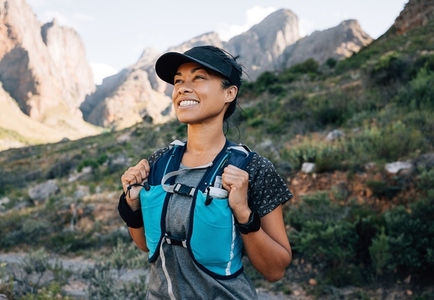 Smiling middle aged female relaxing during a hike  enjoying the view  Female in hiking sportswear looking on mountains