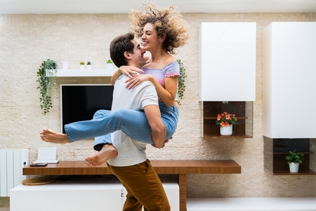 Happy young couple embracing while having fun at home