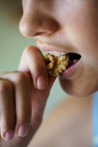 Anonymous girl eating healthy walnut kernel at home
