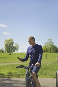 Mature Man in Park with Bicycle Listening to Music on Smartphone