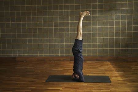 Mature Man Practicing Yoga Headstand