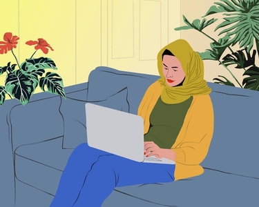 Young woman in hijab working form home at laptop on living room sofa