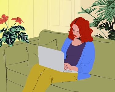 Woman with red hair working from home at laptop on living room sofa