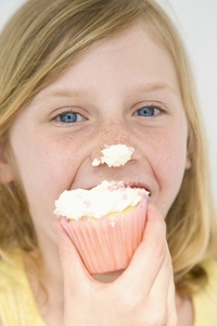 Young Girl Biting Cupcake with Icing on Nose