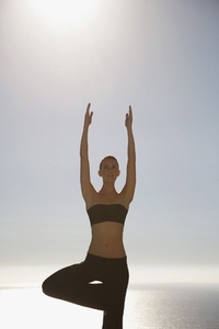 Young woman practicing yoga with ocean in the background