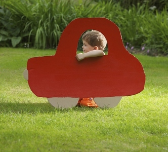 Young Boy Kneeling behind Cardboard Cut Out in Shape of Car