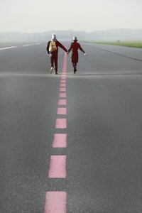 Couple Running along Airport Runway Holding Hands