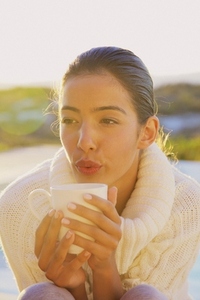 Young Woman Blowing on Hot Drink