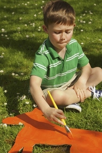 Boy Painting Cardboard Cut Out in Garden