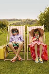 Boy and Girl Wearing Straw Hat and Sunglasses Sitting on Deck Chairs