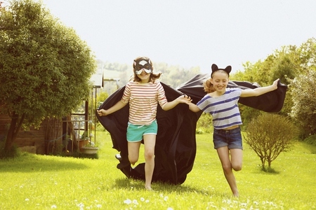 Young Girls Wearing Cape and Mask Running in Garden