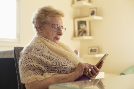 Senior woman in shawl using smart phone at home
