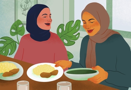 Women friends in hijabs eating together at table