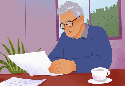 Senior man with tea reviewing paperwork at table at home