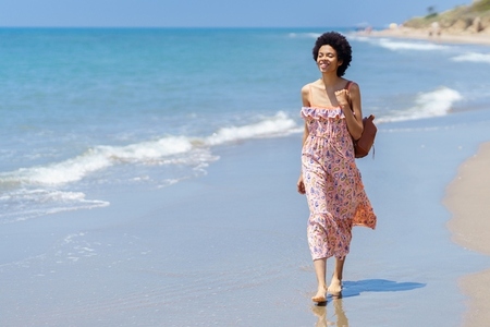 Happy ethnic woman on sandy seashore