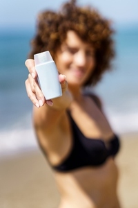 Woman in bikini showing cosmetic product