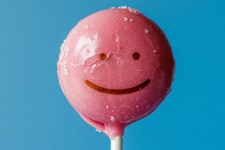 Lollipop in the shape of an smile emoji on a blue background.
