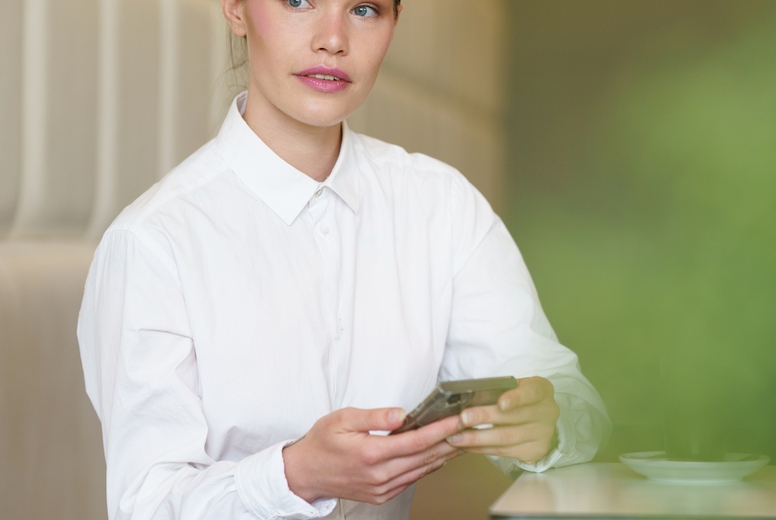 Businesswoman using phone sitting in a cafeteria