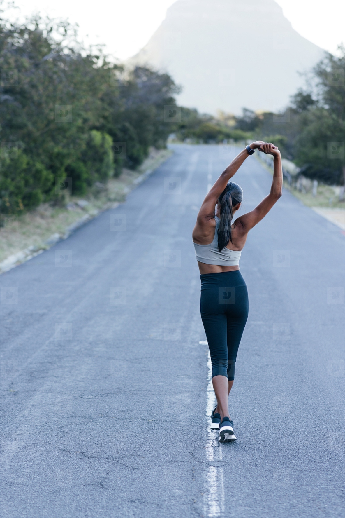 Full length slim female walking on an abandoned road and warming up her body before an outdoor workout