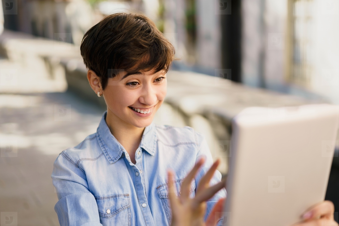A Cheerful Young Woman Engaged in an Enjoyable Video Call While Outdoors in Daylight