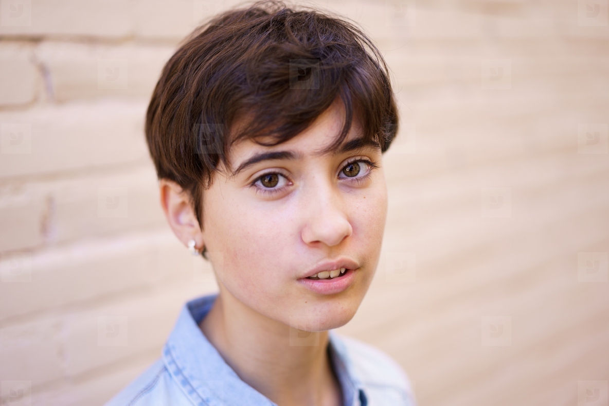 A Portrait of a Young Person with Short Hair Set Against a Soft and Gentle Background