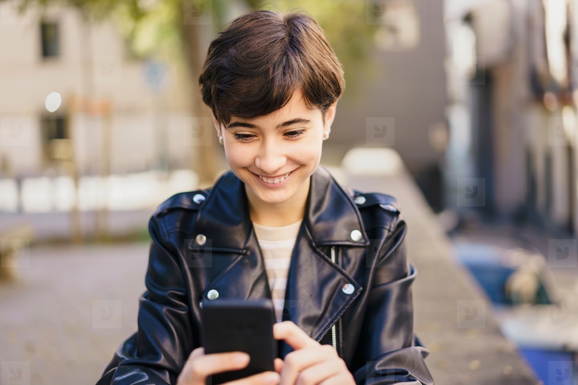 A Cheerful Young Woman Actively Engaged with Her Smartphone While Enjoying the Outdoors
