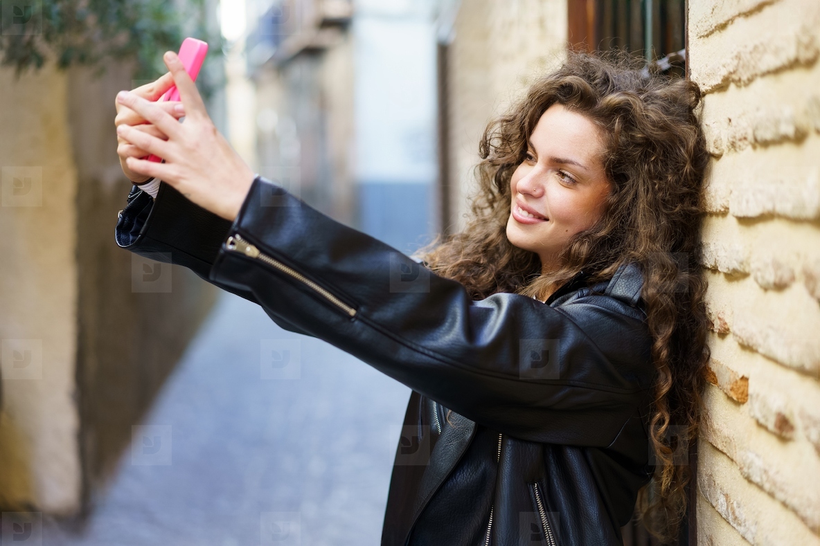 A Young Woman Enthusiastically Taking a Selfie in a Colorful Urban Alleyway Scene