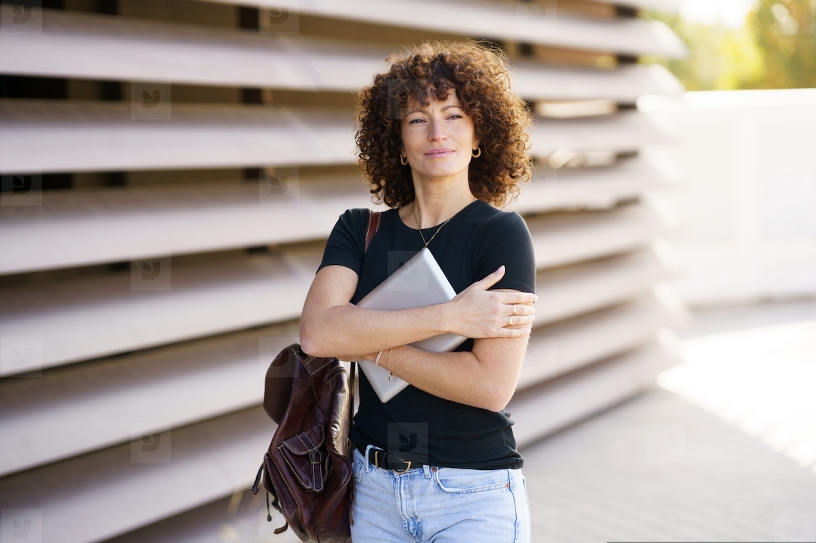 A Confident Businesswoman Working on Her Laptop in a Modern Urban Cityscape Setting