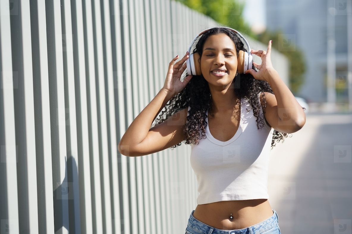 A Joyful Young Woman is Seen Enjoying Great Music in a Lively Urban Setting with Headphones