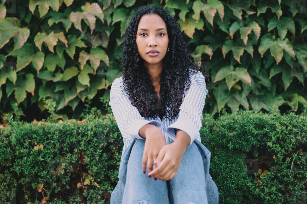 A contemplative young woman sits peacefully in lush greenery  embodying elegance and calm