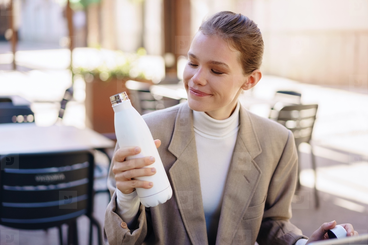 A Woman Happily Enjoying Her Colorful Water Bottle While Seated in a Cafeteria Setting