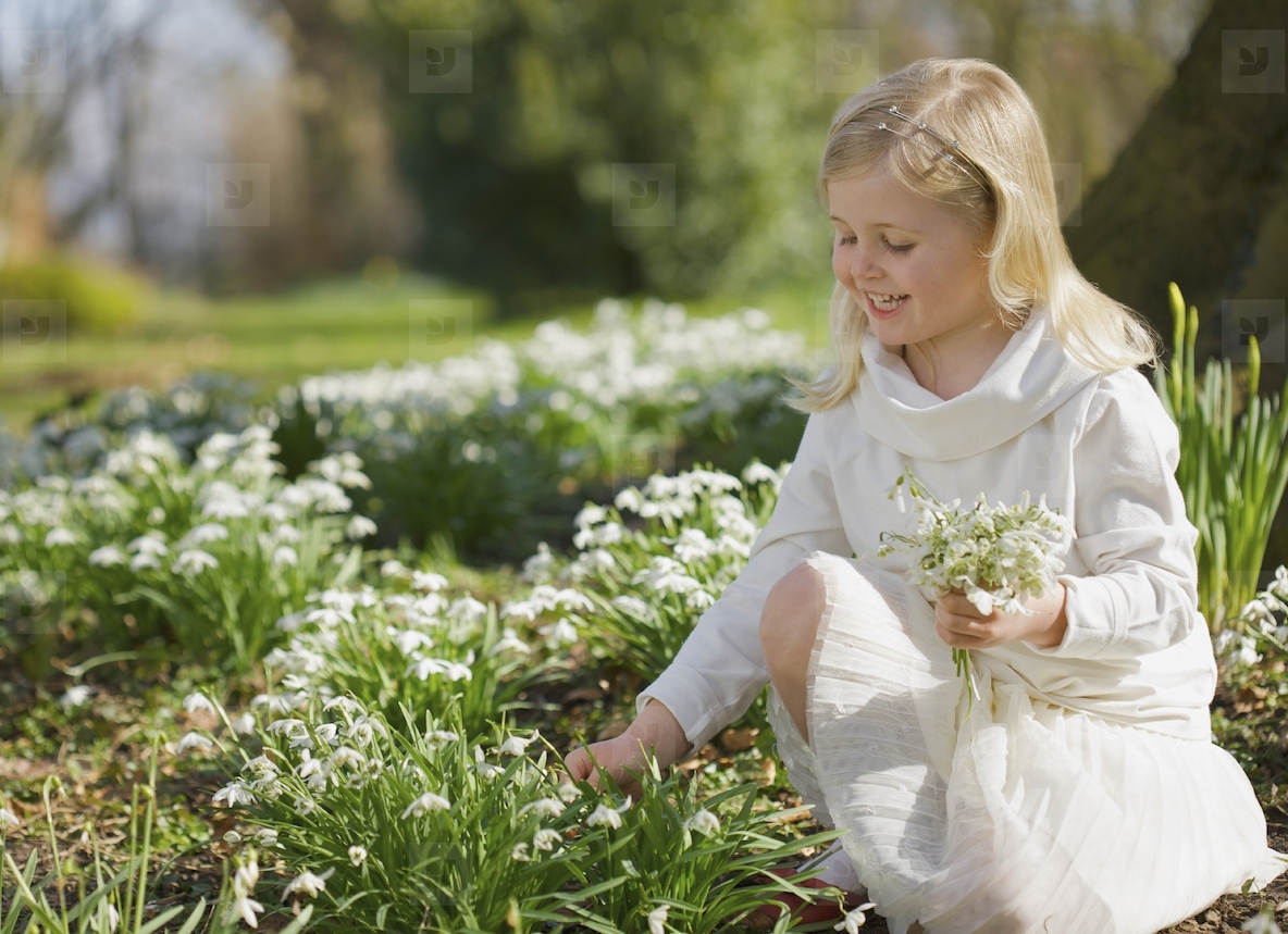 Portrait of a smiling young girl picking snowdrops