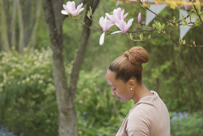 Masseuse giving a woman a facial massage under a magnolia tree