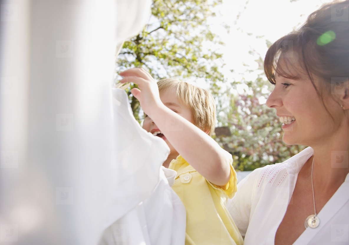 Young boy helping mother hanging linens on a clothesline
