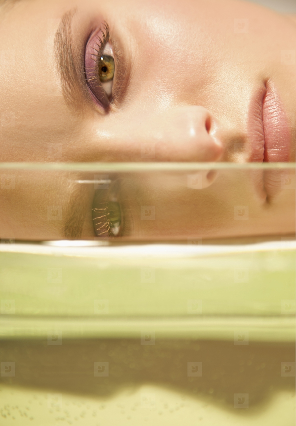 Close up of a young woman face lying behind a glass container