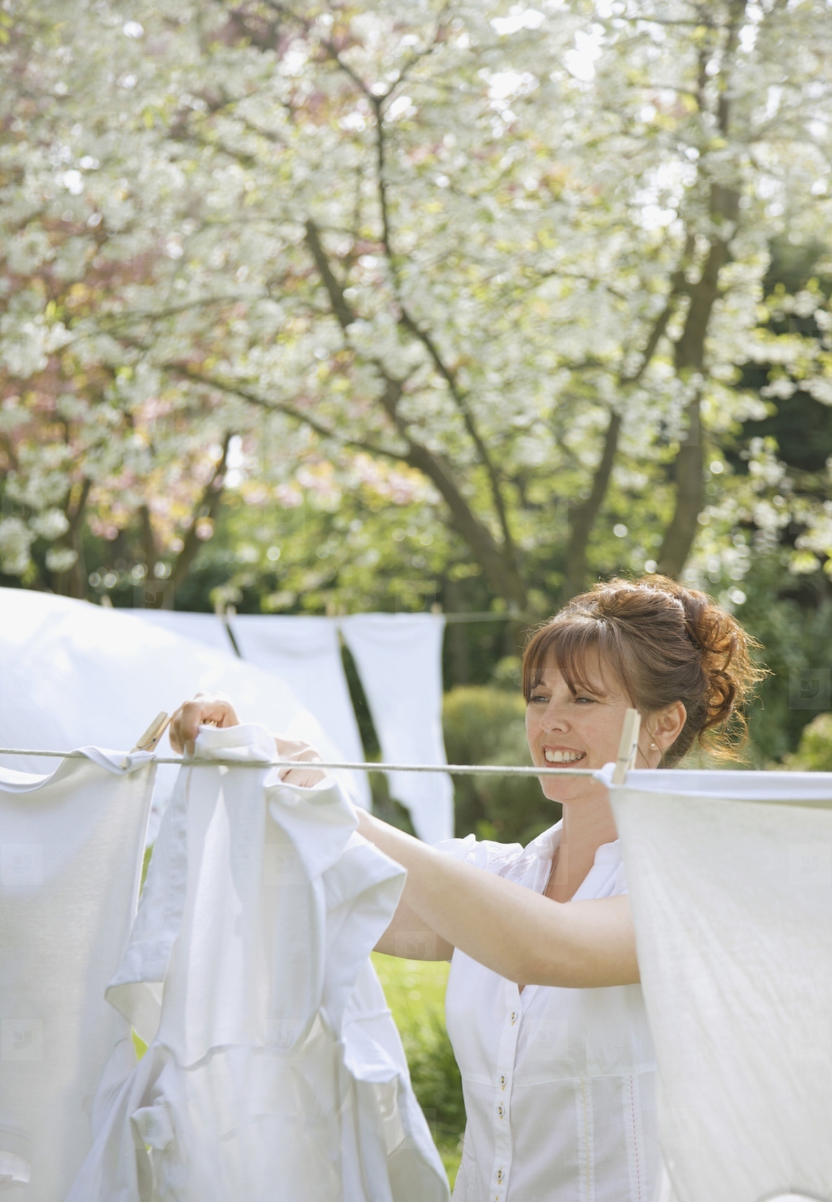 Smiling woman hanging linens on a clothesline