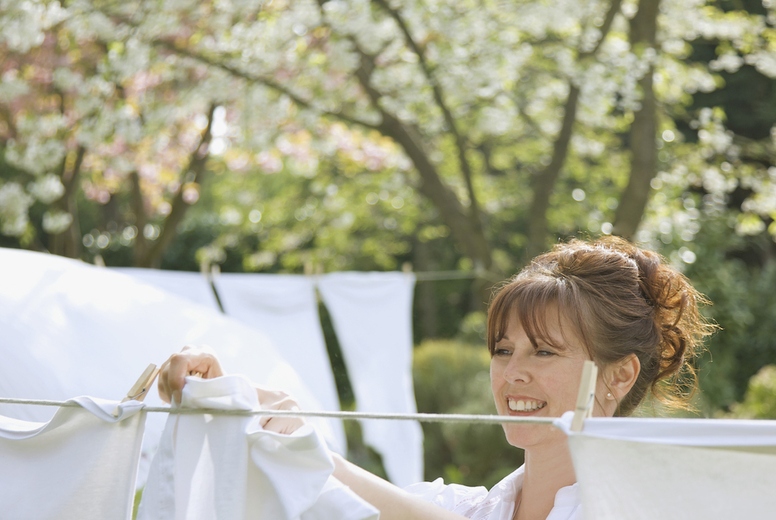 Smiling woman hanging linens on a clothesline