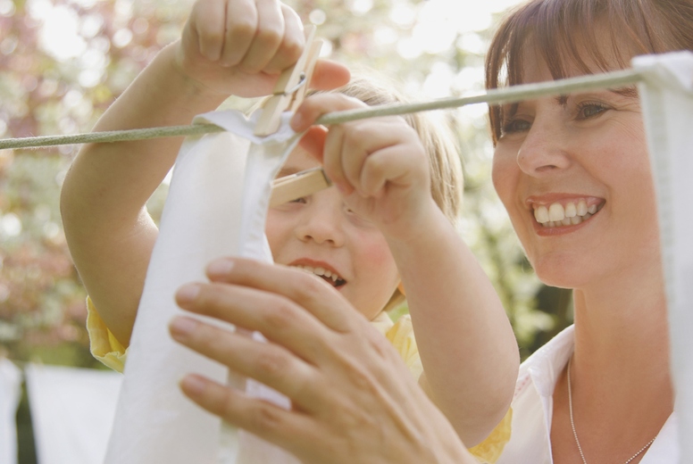 Young boy helping mother hanging linens on a clothesline