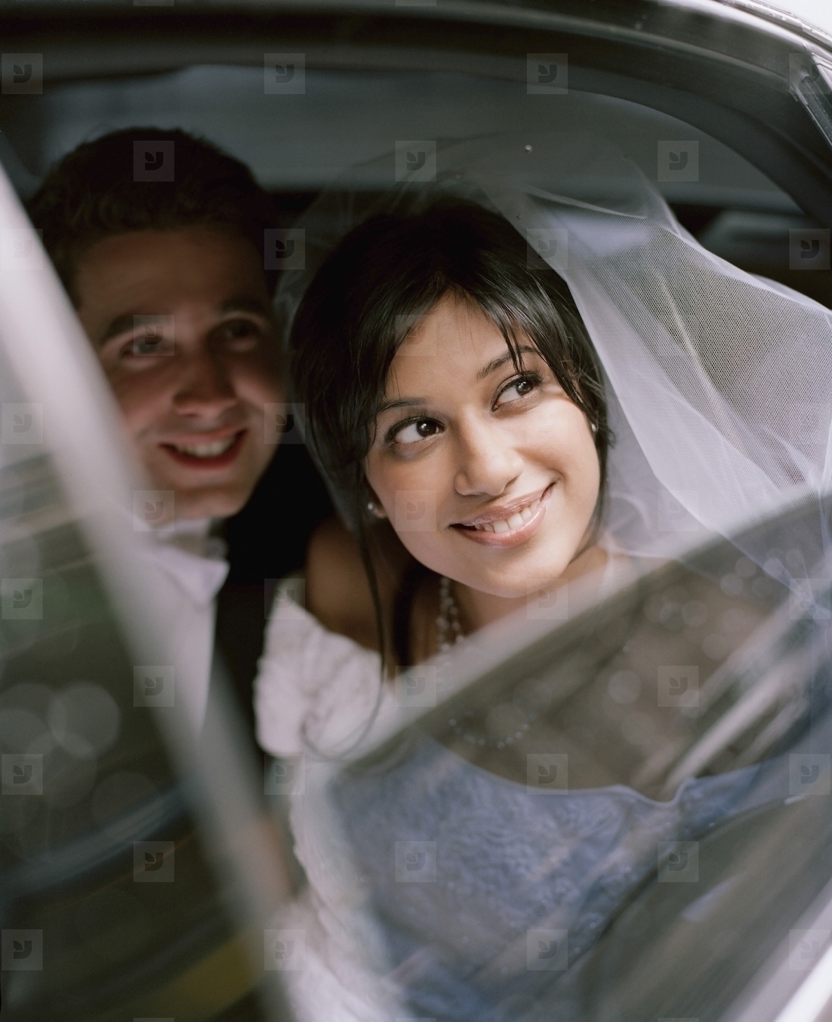 Bride and groom sitting inside a car